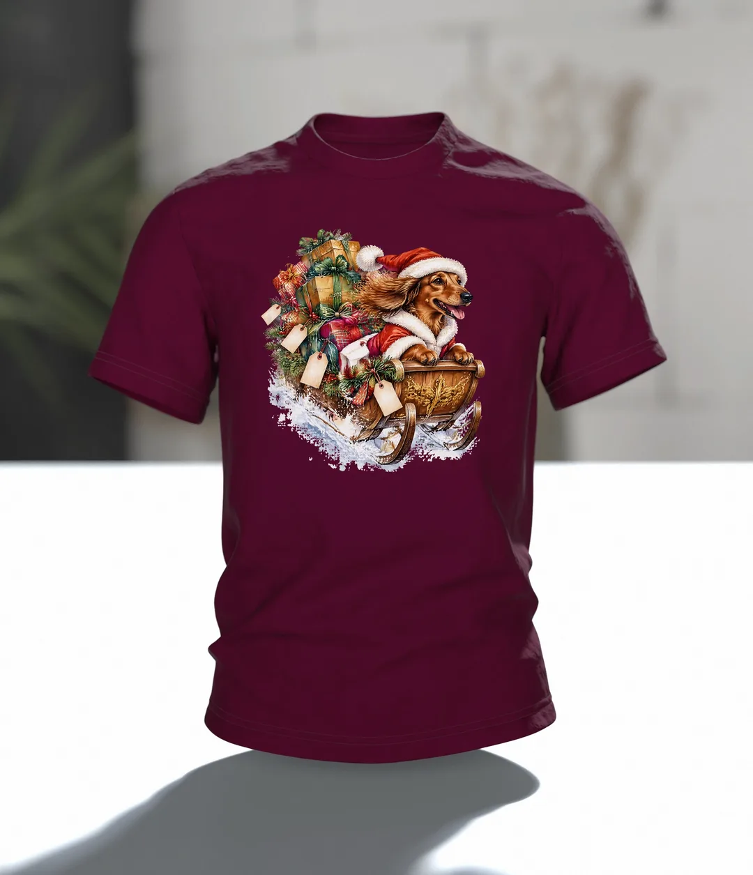 Weihnachtshund T-Shirt: Dackel als Weihnachtsmann im Geschenkeschlitten, Aquarell mit Blockhütte im Schnee auf dem Rücken, Im Raum